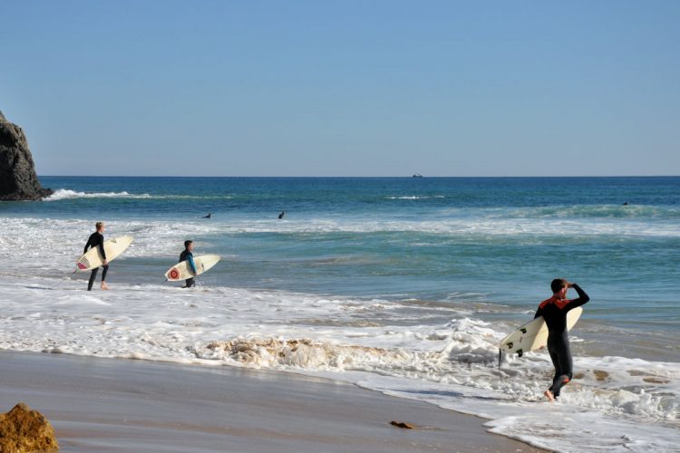 Surfers taking in the views at Black Rock, Praia da Luz