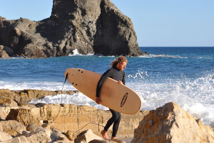An AltaVista surfer with wetsuit and board at Black Rock, Praia da Luz